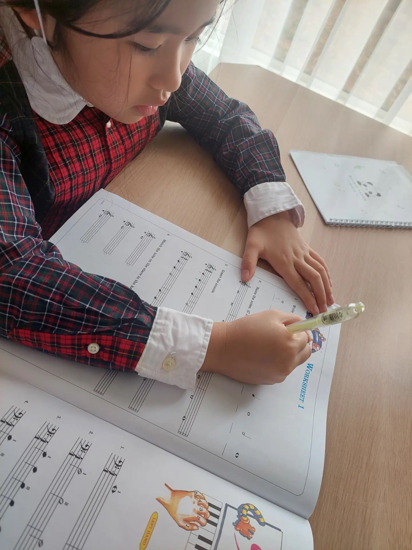Murid menulis not di buku latihan